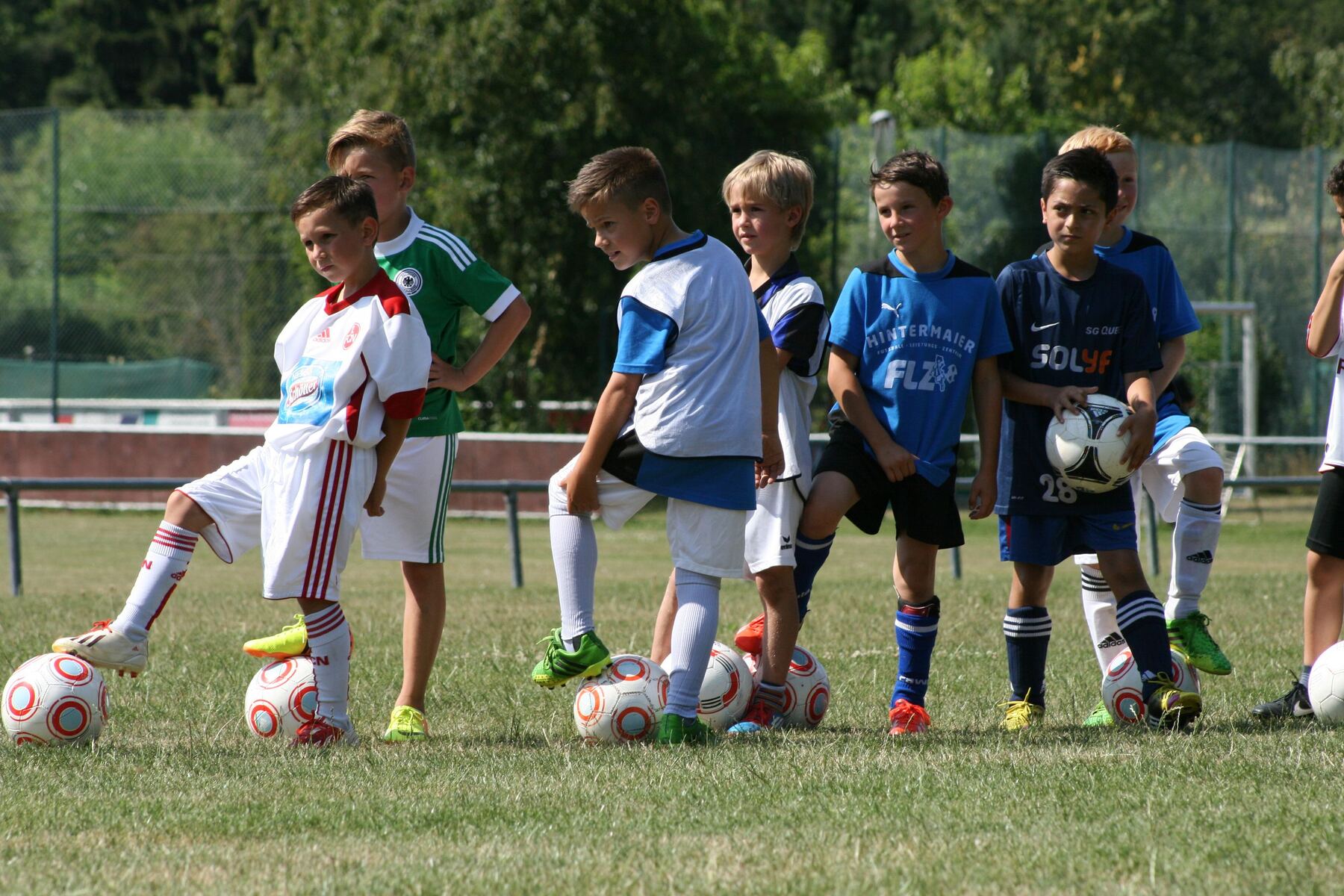 Kinder stehen mit Bällen in einer Reihe beim Training der FLZ-Fußballschule